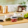 Kitchen counter with food storage containers filled with produce. Náhled obrázku produktu