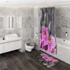 A modern bathroom with marble-tiled walls and dark wood flooring, featuring a toilet with a decorative seat cover, a shower curtain with a floral print, and a matching bath mat. Produktbild-Vorschau