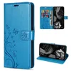 A collage of images showing a blue flip phone case with a floral and butterfly design, including views of the case open with cards and cash, and the case used as a stand. Produktbild-Vorschau