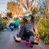 Two children are riding on trikes on a sidewalk, wearing festive hats and glasses. Anteprima dell’immagine prodotto
