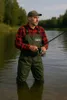 A man is fishing in a river while wearing waders. Produktbild-Vorschau