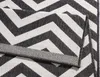 A close-up view of a black and white geometric patterned rug, folded over itself. Voir les images du produit