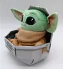 A plush toy of 'The Child' from Star Wars, also known as Baby Yoda, sitting in its pram-like carrier. Produktbild-Vorschau