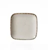 A square plate with a speckled white surface and a distressed brown rim, isolated on a white background. Produktbild-Vorschau