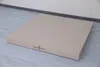 A beige, two-part gymnastics mat is lying flat on a light gray floor, against a white wall with a dark gray baseboard. Náhled obrázku produktu