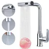 A chrome kitchen faucet with water flowing, and a peach being rinsed under the water. Produktbild-Vorschau