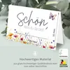 A folded greeting card with floral and butterfly illustrations, showing dimensions and material information below. Produktbild-Vorschau