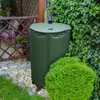 A green rain barrel is placed next to a wooden fence and lush green foliage in a garden setting. Náhled obrázku produktu