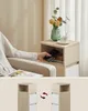 A person is placing a phone into a nightstand next to a chair. Náhled obrázku produktu