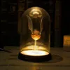 A golden snitch under a glass dome, lit from below, on a wooden surface with books in the background. Podgląd zdjęcia produktu