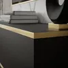 A close-up view of a black cabinet with a gold trim and books on top. Produktbild-Vorschau