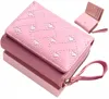 A pink wallet with a heart pattern is displayed on a pink surface. Anteprima dell’immagine prodotto