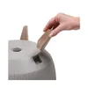 A hand is inserting a brown wedge into a gray planter. Náhľad obrázku produktu
