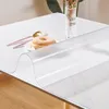 A transparent table protector is laid over a wooden table, with a donut and cutlery on a plate placed on top. Náhled obrázku produktu