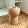 A cork stool shaped like a champagne cork, with a champagne print on top, is placed on a wooden floor next to a shower stall. Produktbild-Vorschau