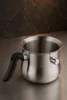 A stainless steel pot with a black handle sits on a metallic surface, with a dark, marbled background. Produktbild-Vorschau