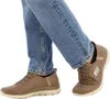 A person wearing blue jeans and brown Skechers slip-on shoes. Produktbild-Vorschau