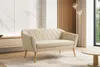 A beige sofa with diamond quilting and wooden legs is placed in a modern living room with a marble wall and wooden paneling. Anteprima dell’immagine prodotto