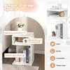 A white S-shaped side table with storage compartments, shown with decorative items and books. Podgląd zdjęcia produktu