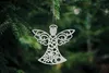 A white angel ornament hangs from a pine branch. Náhled obrázku produktu