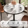 A round marble-top table with a black pedestal base, set in a dining area with chairs and a window view. Anteprima dell’immagine prodotto