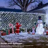 A child dressed as Santa Claus is decorating a snowy yard with Christmas lights, inflatable snowman, penguin, and gifts. Produktbild-Vorschau