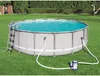 An above-ground swimming pool set up on a grassy lawn, with a filter pump and hoses connected. Voir les images du produit