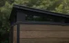 Close-up view of the top section of a shed, showing the roofline, a long horizontal window, and the wood-effect siding. Náhľad obrázku produktu