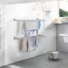 A laundry drying rack mounted on a wall in a room with a window and a basket on the floor. Náhľad obrázku produktu