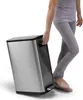 A person is using a foot pedal to open a stainless steel trash can. Produktbild-Vorschau