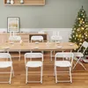 A dining table set up for a holiday meal with chairs around it and a Christmas tree in the background. Podgląd zdjęcia produktu
