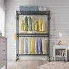 A garment rack filled with colorful clothing in a room with white paneled walls. Voir les images du produit