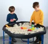 Two young boys are playing with kinetic sand in a black play tray with blue legs. Produktbild-Vorschau
