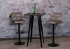 Two bar stools and a high table are set up against a stone wall. Podgląd zdjęcia produktu