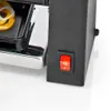 A close-up of a raclette grill with food items in the tray and a red power switch. Náhľad obrázku produktu