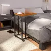 A laptop and coffee cup sit on a C-shaped side table next to a bed. Anteprima dell’immagine prodotto