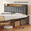 A bed frame with a headboard shelf and underbed storage, shown with decorative items and storage baskets. Podgląd zdjęcia produktu