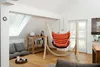 A cozy living room with a hammock chair, floor cushions, and a bookshelf. Produktbild-Vorschau