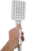 A hand holding a chrome shower head with a white button. Náhled obrázku produktu