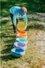 A child is playing with a set of colorful stacking stones in a sandy outdoor area. Anteprima dell’immagine prodotto