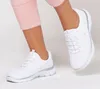 A person's legs wearing white Skechers sneakers and pink capri pants. Náhled obrázku produktu