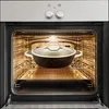 A deep frying pan with a lid is placed on a rack inside an open oven. Náhľad obrázku produktu