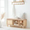 A wooden shoe bench with storage is placed in a hallway or entryway, with a coat hanging on a wall-mounted rack above it. Produktbild-Vorschau