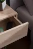 A close-up view of an open drawer in a wooden nightstand, revealing a black object inside. Náhled obrázku produktu