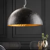 A black and gold pendant lamp hanging over a dark table. Produktbild-Vorschau