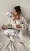 A pregnant woman is lying on a bed, reading a book and resting her hand on her belly. She is surrounded by pillows, one of which is a pregnancy pillow. Náhľad obrázku produktu