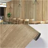 A collage showing a restaurant interior with wood-paneled walls and tables, and a close-up of a roll of wood-patterned adhesive vinyl. Anteprima dell’immagine prodotto