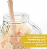 A close-up shot of a glass jar filled with fermented food, with a wooden tamper inside. Podgląd zdjęcia produktu