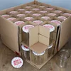 A cardboard box filled with glass jars with decorative lids. Podgląd zdjęcia produktu