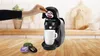 A person is inserting a coffee pod into a coffee machine with a mug underneath. Produktbild-Vorschau